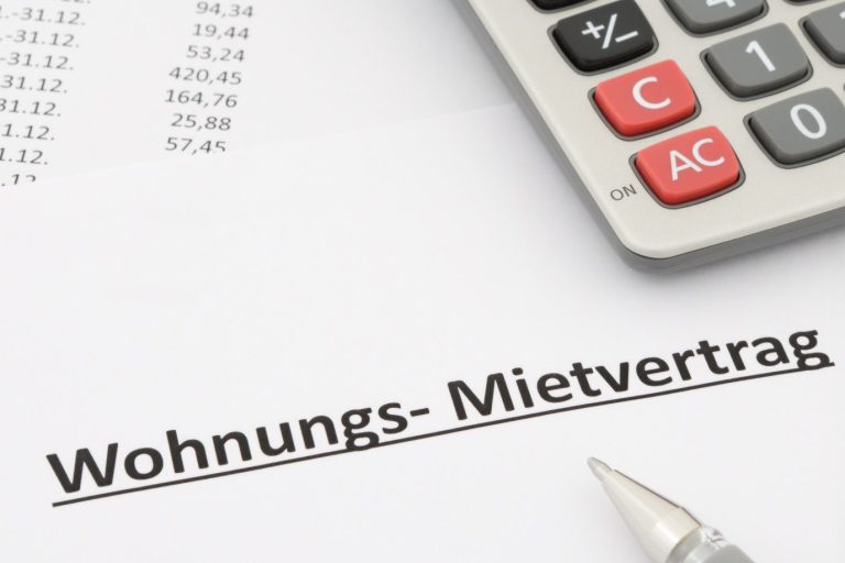 Wohnungsmietvertrag auf einem Tisch mit einem Taschenrechner und einem Stift.